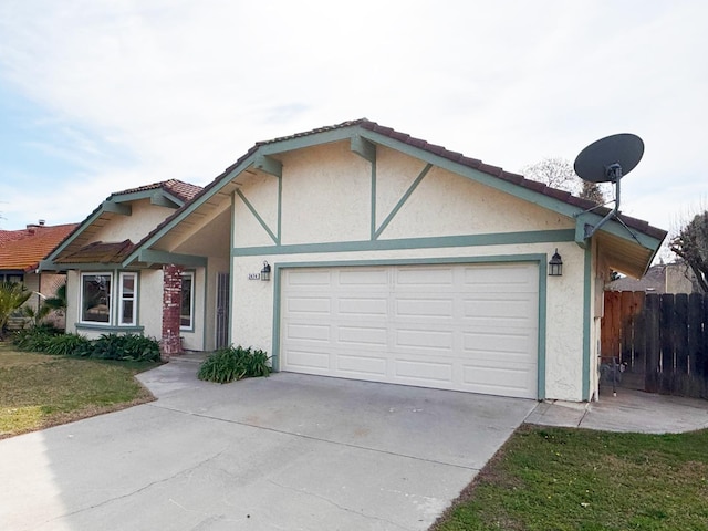 view of front of property featuring an attached garage, fence, concrete driveway, stucco siding, and a front lawn