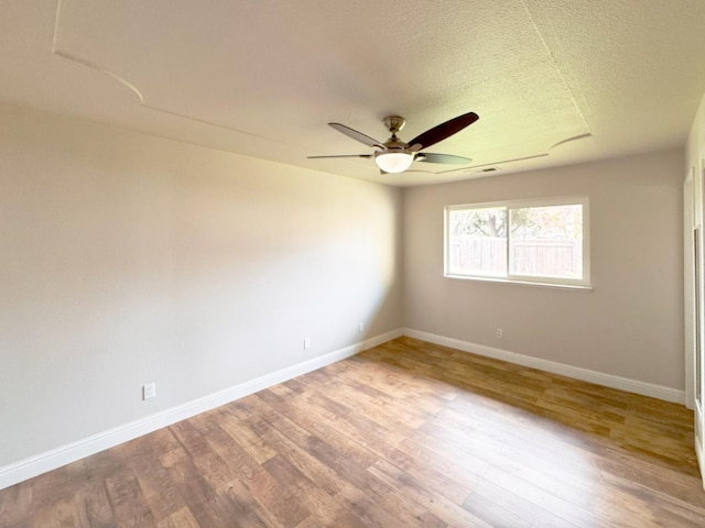 spare room with ceiling fan, a textured ceiling, baseboards, and wood finished floors