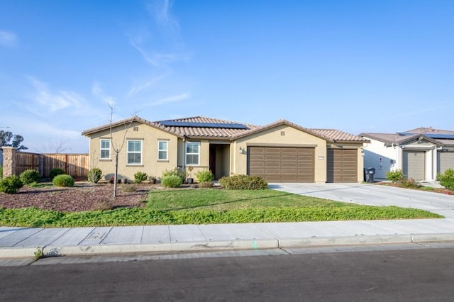 view of front of home featuring driveway, an attached garage, fence, roof mounted solar panels, and stucco siding