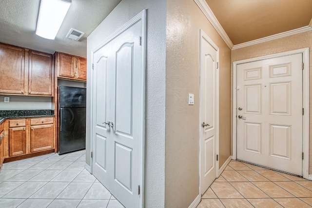 kitchen with visible vents, dark countertops, freestanding refrigerator, and brown cabinets