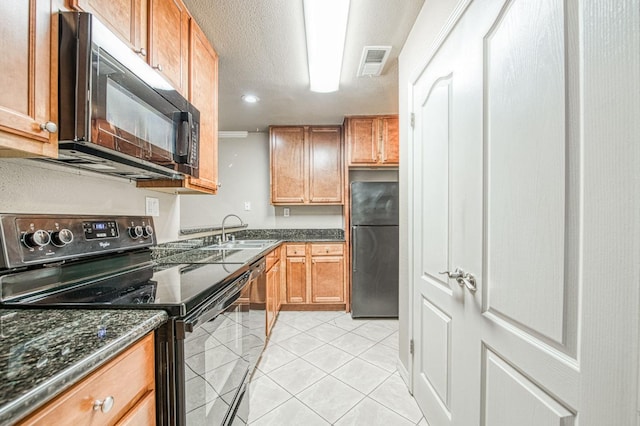 kitchen featuring black appliances, brown cabinetry, a sink, and visible vents