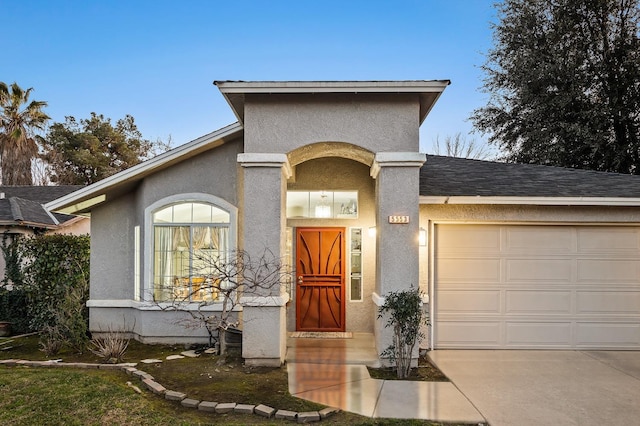 view of front of property with driveway, an attached garage, and stucco siding