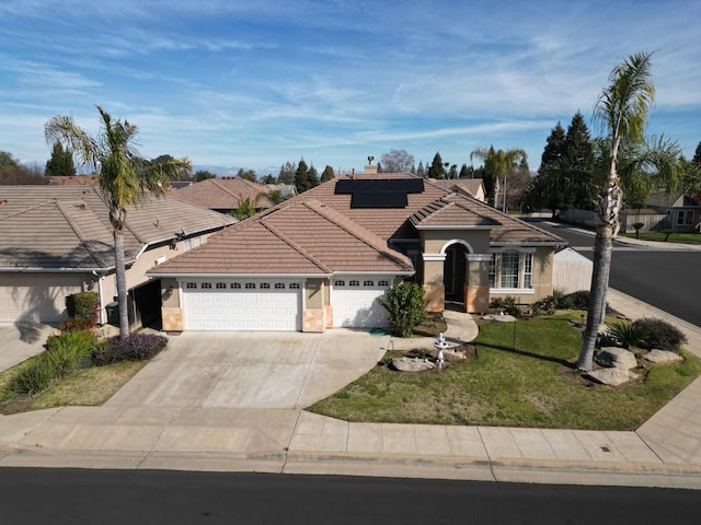 view of front of house featuring a garage, solar panels, a tile roof, concrete driveway, and a front yard