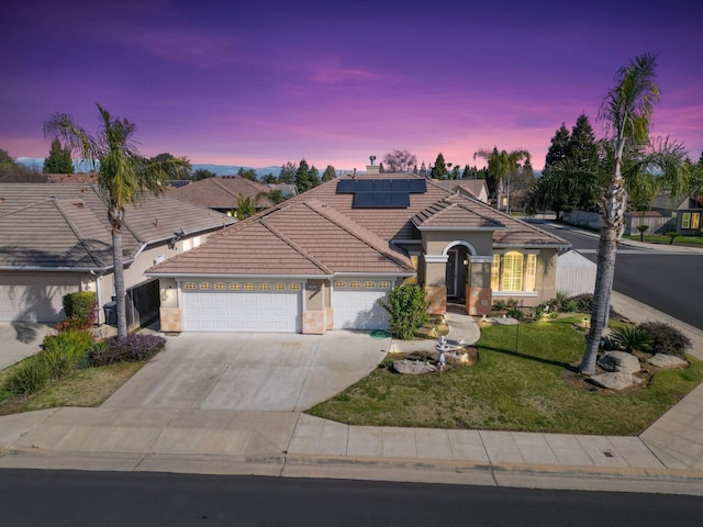 mediterranean / spanish-style house featuring solar panels, concrete driveway, an attached garage, a front yard, and a tiled roof