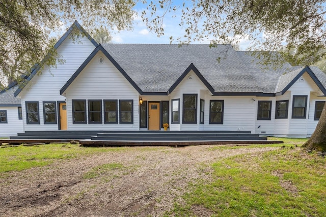 back of property featuring a shingled roof and a yard