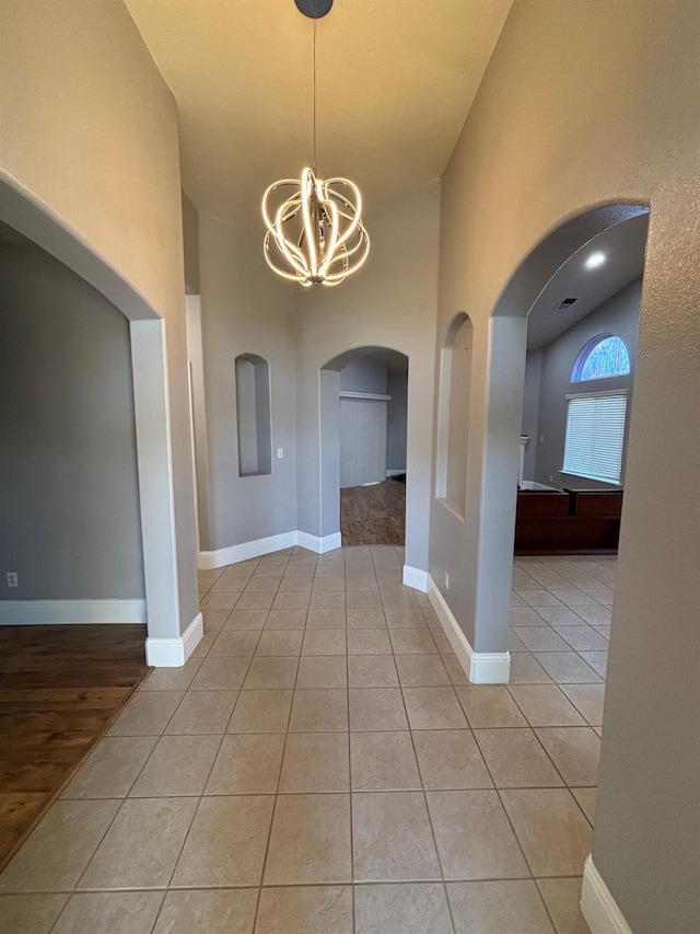 2136 Florence Ave, Sanger, CA 93657 - unfurnished dining area with a notable chandelier, baseboards, light tile patterned flooring, high vaulted ceiling, and arched walkways