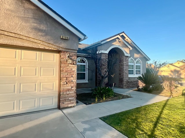 view of front of property featuring a garage, stone siding, and stucco siding