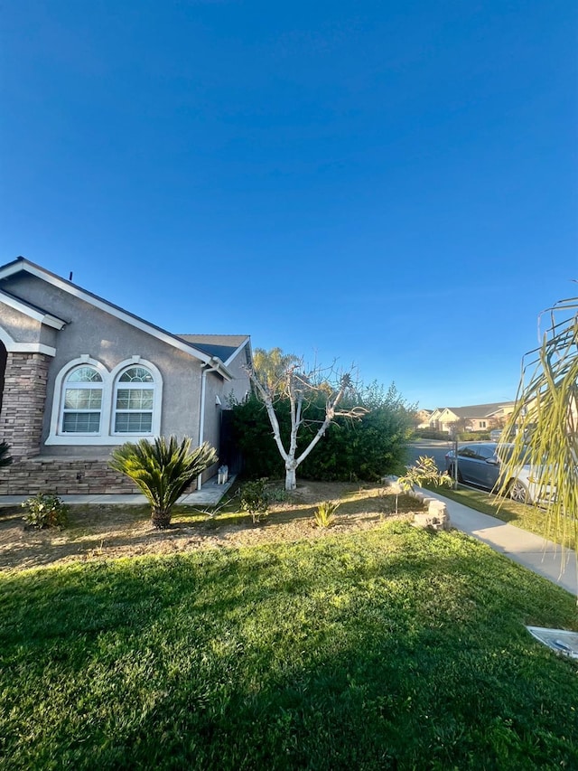 view of side of home featuring a yard and stucco siding