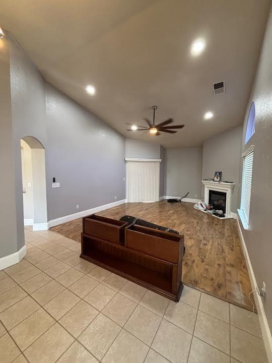 2136 Florence Ave, Sanger, CA 93657 - living area with visible vents, light tile patterned floors, arched walkways, ceiling fan, and a fireplace