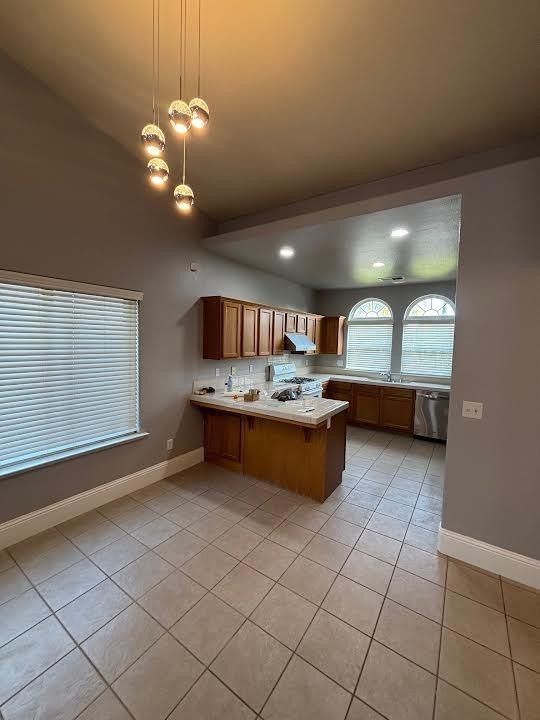 2136 Florence Ave, Sanger, CA 93657 - kitchen with a peninsula, light countertops, light tile patterned flooring, brown cabinets, and stainless steel dishwasher