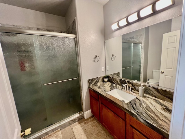 bathroom featuring a shower stall, toilet, and vanity