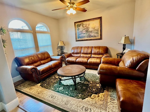 living area featuring a ceiling fan, baseboards, and wood finished floors