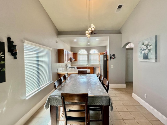 dining space featuring arched walkways, visible vents, baseboards, and light tile patterned floors