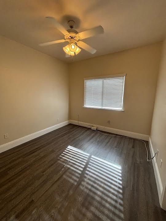 2136 Florence Ave, Sanger, CA 93657 - unfurnished room featuring dark wood-style flooring, baseboards, and a ceiling fan