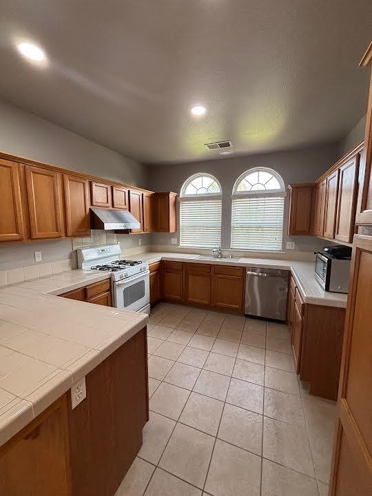 2136 Florence Ave, Sanger, CA 93657 - kitchen with white gas range, under cabinet range hood, visible vents, dishwasher, and a sink