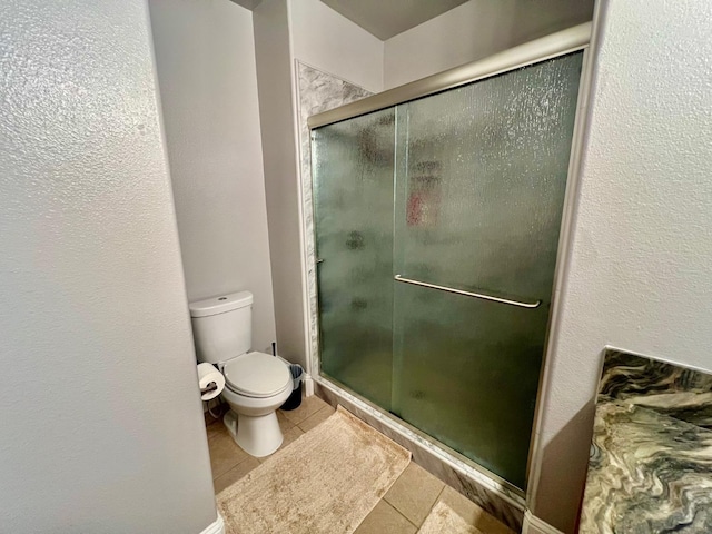 full bath featuring a stall shower, toilet, and tile patterned floors