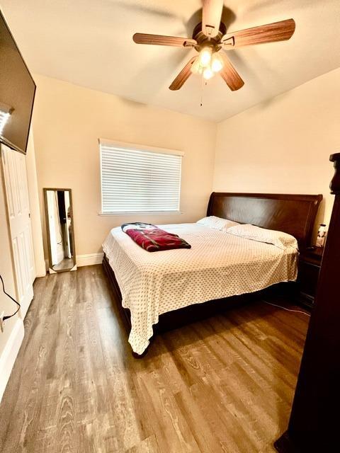 bedroom featuring ceiling fan, wood finished floors, and baseboards