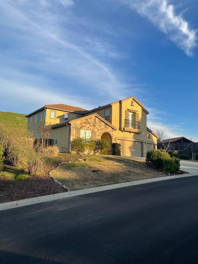 view of front of property featuring an attached garage, stone siding, driveway, and stucco siding