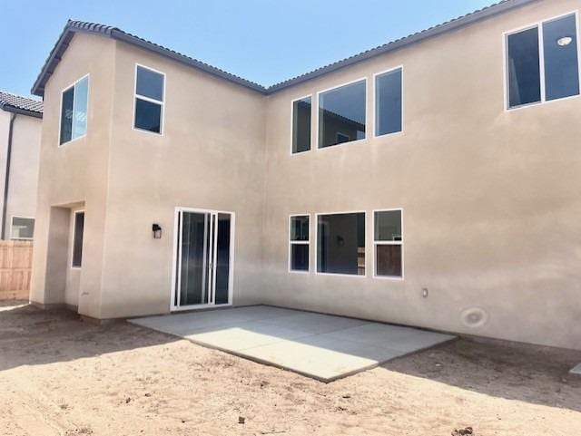 rear view of house with stucco siding and a patio