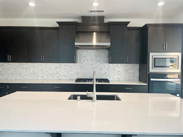 kitchen with dark cabinets, light countertops, a sink, and oven