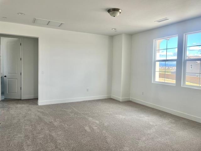 unfurnished room with baseboards, carpet flooring, and visible vents