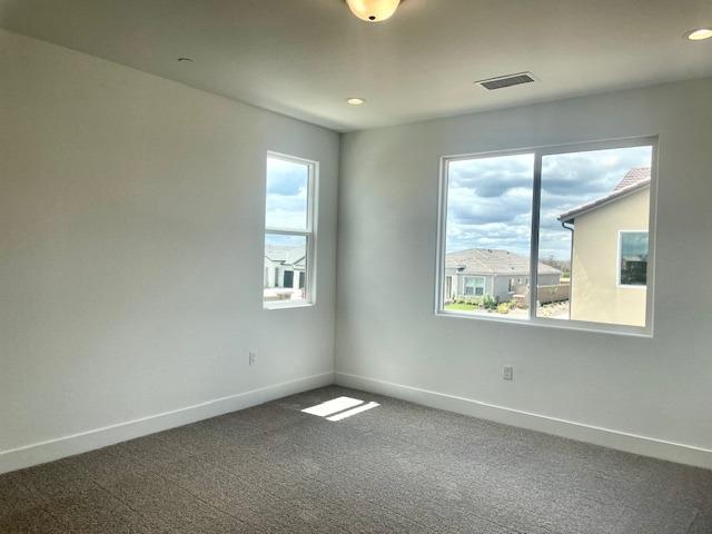 carpeted empty room with a healthy amount of sunlight, baseboards, recessed lighting, and visible vents