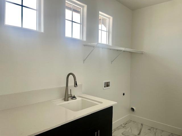 laundry room featuring electric dryer hookup, a sink, baseboards, hookup for a washing machine, and marble finish floor