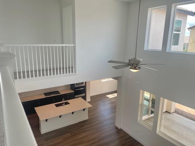 interior space with a ceiling fan, wall oven, wood finished floors, a sink, and baseboards