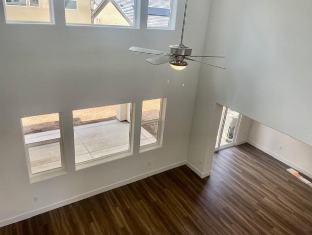 interior space featuring baseboards, ceiling fan, and dark wood-style flooring