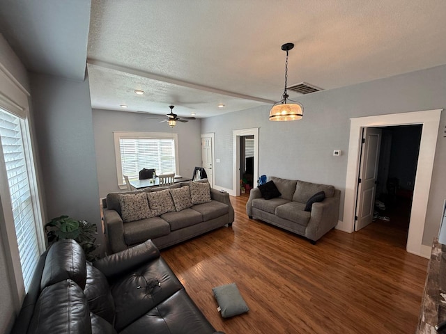 living area featuring dark wood-style floors, visible vents, a textured ceiling, and baseboards