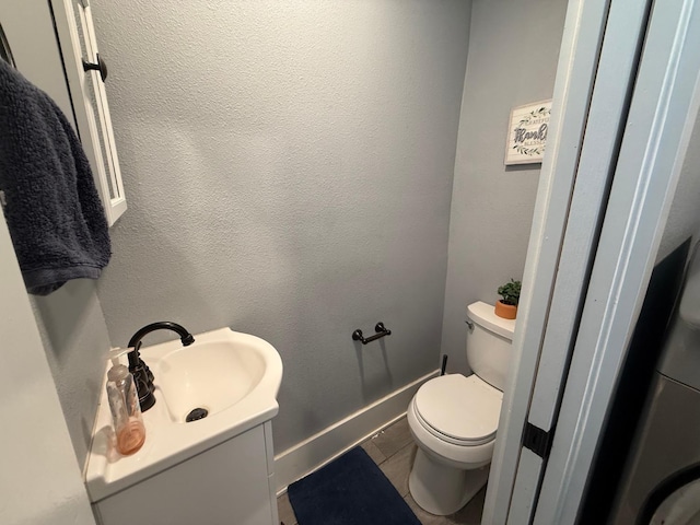 bathroom featuring toilet, tile patterned flooring, baseboards, and a textured wall