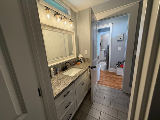 bathroom featuring baseboards, wood finished floors, and vanity