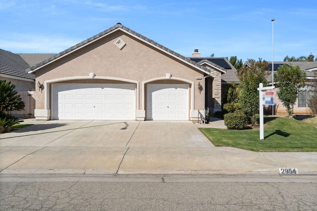 view of front of property featuring a tile roof, driveway, an attached garage, and stucco siding