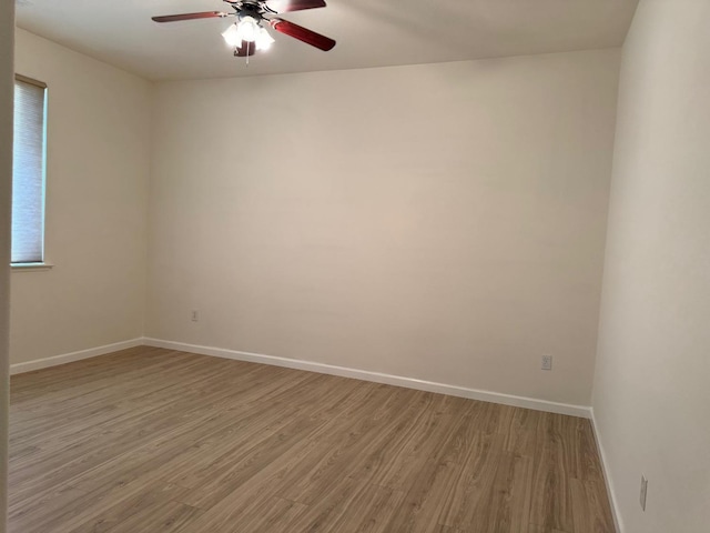 spare room featuring ceiling fan, light wood-style flooring, and baseboards