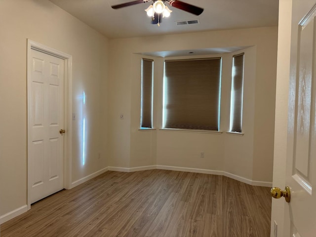 empty room featuring light wood-style floors, visible vents, baseboards, and a ceiling fan