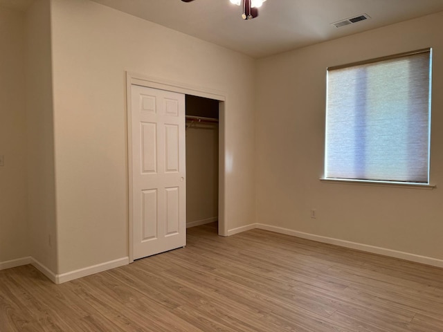 unfurnished bedroom with light wood finished floors, a closet, visible vents, a ceiling fan, and baseboards