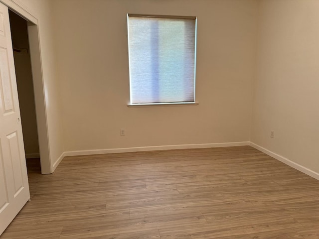 spare room featuring light wood-type flooring and baseboards