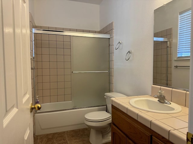 bathroom featuring toilet, shower / bath combination with glass door, tile patterned flooring, and vanity