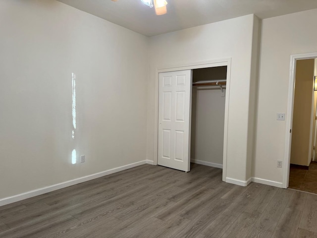 unfurnished bedroom featuring a closet, wood finished floors, and baseboards