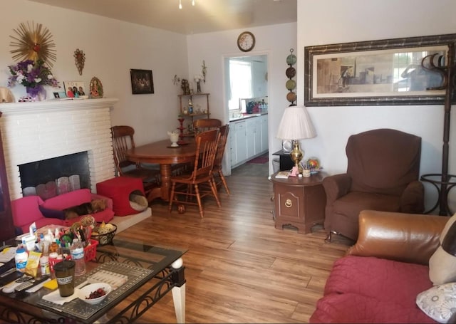 living room featuring light wood-type flooring and a brick fireplace