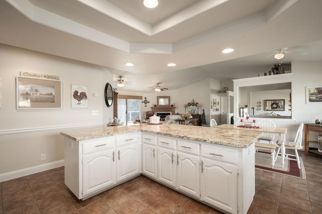 kitchen featuring recessed lighting, a fireplace, white cabinetry, and a tray ceiling