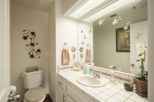 half bathroom featuring visible vents, toilet, and vanity