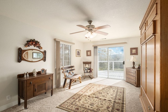 sitting room featuring visible vents, light colored carpet, a textured ceiling, and ceiling fan