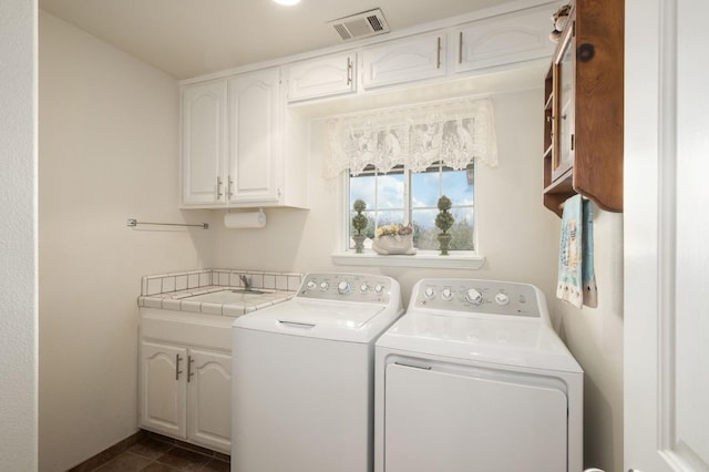 clothes washing area with visible vents, cabinet space, a sink, dark tile patterned floors, and washer and clothes dryer