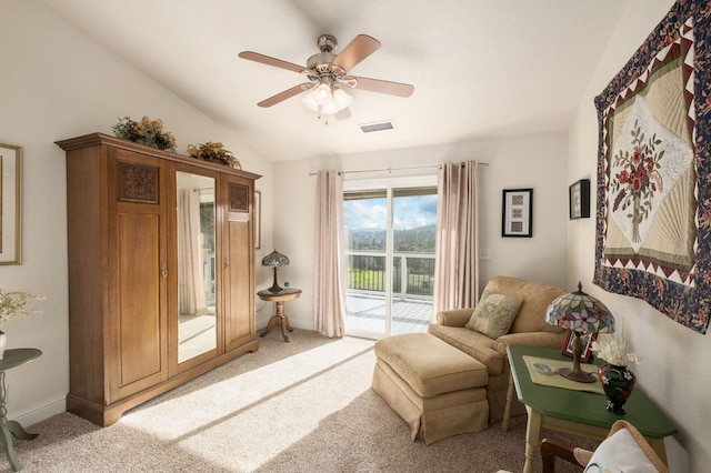 living area with visible vents, baseboards, lofted ceiling, ceiling fan, and light colored carpet