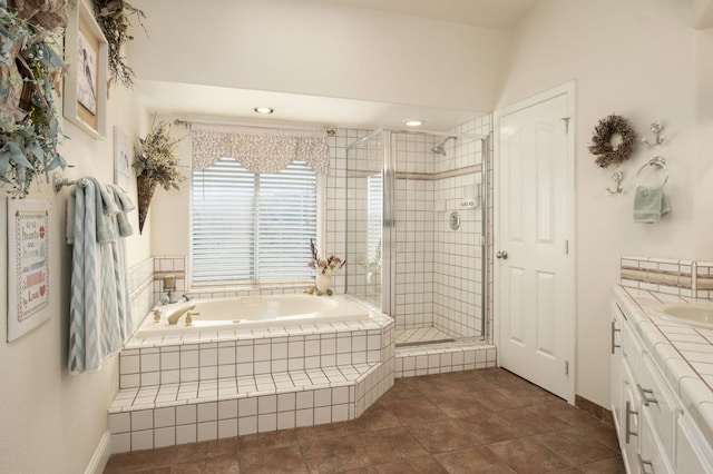 bathroom with baseboards, a shower stall, vanity, and a garden tub