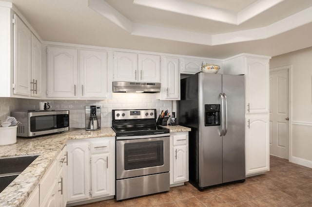 kitchen featuring under cabinet range hood, backsplash, appliances with stainless steel finishes, and a raised ceiling