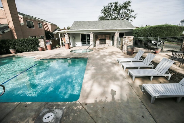 community pool with a patio area, fence, an outdoor structure, and a hot tub