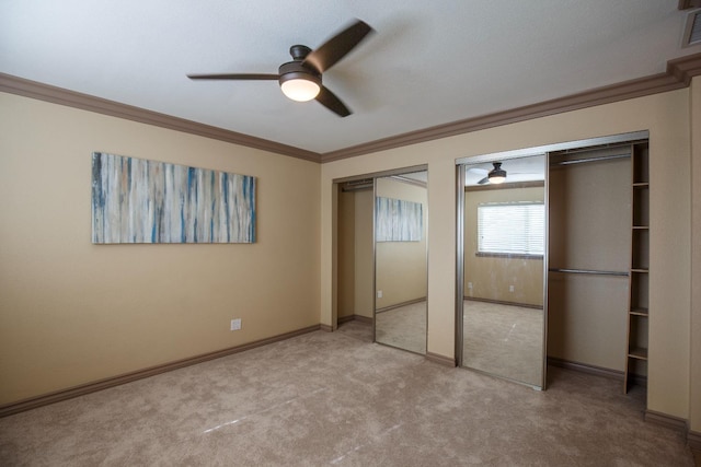 unfurnished bedroom with baseboards, ornamental molding, two closets, and light colored carpet