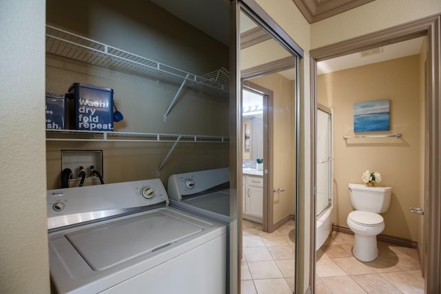 laundry area with light tile patterned floors, laundry area, washing machine and clothes dryer, and baseboards